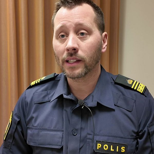 Polis i uniform sitter vid ett bord inomhus.