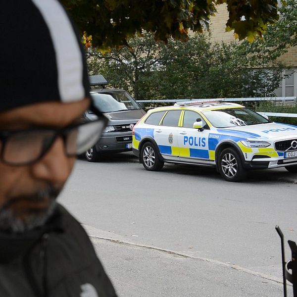 En man och en polisbil i Jordbro efter skjutningen.
