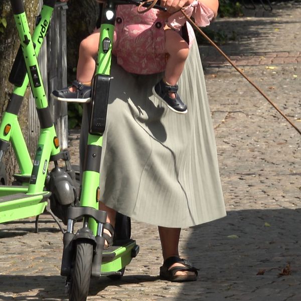 En delad bild som visar två olika scener. Den vänstra sidan visar en person med långt hår i en svart tröja, och den högra sidan visar en kvinna i en lång, ljusgrå kjol som står vid en grön el-scooter medan hon håller ett barn. Det framgår att de befinner sig på en asfalterad väg.