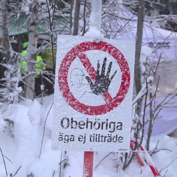 Varningsskylt om tillträdesförbud står i ett snötäckt skogsområde.