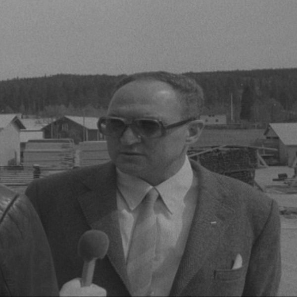 en man står och blir intervjuad av en reporter – svartvit bild