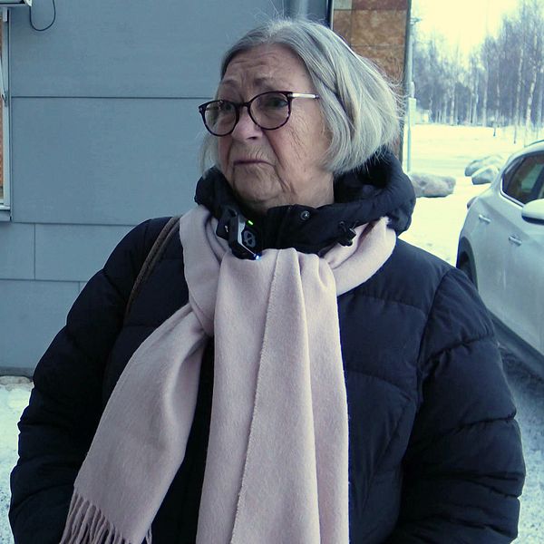 Christina utomhus i vinterkläder, frustrerad över svårigheter att nå hälsocentraler i Norrbotten.