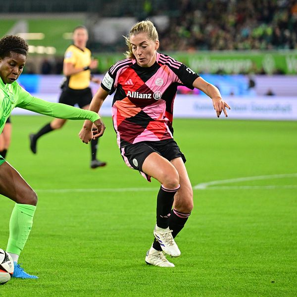 Två damfotbollsspelare i kamp om bollen under en match på en gräsplan.