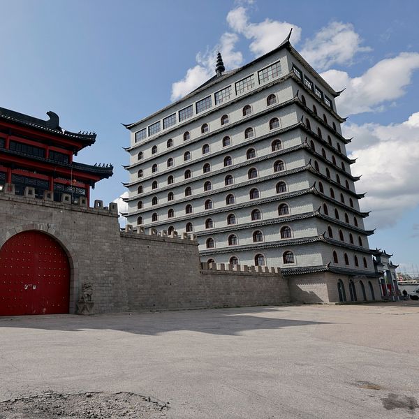 Dragon Gate-hotellets fasad med mur, port och huvudbyggnad under blå himmel.