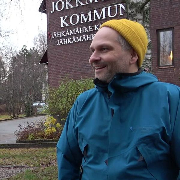 Henrik Blind utanför kommunhuset i Jokkmokk, klädd i blå jacka och gul mössa.
