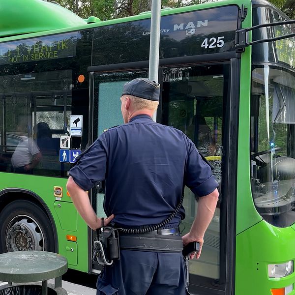 Polis står framför en buss vars fönster skadats i skjutningen