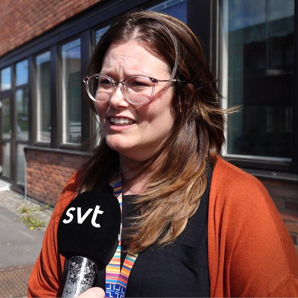 Reporter intervjuar person utanför tegelbyggnad med svt-mikrofon.