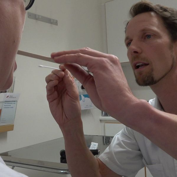 En delad bild som visar två scener. Den vänstra sektionen visar en hand som håller en plastförpackning med tabletter, där flera vita piller är synliga i en metallask. Den högra sektionen visar en person som utför en medicinsk procedur, där en pinne hålls i närheten av en annan persons mun. Bakgrunden ser ut att vara en medicinsk miljö.