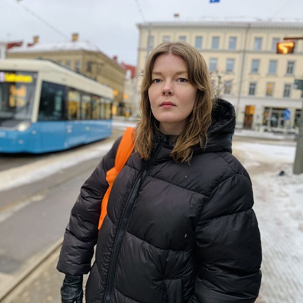 Kvinna i svart dunjacka står vid en spårvagn i Göteborg.