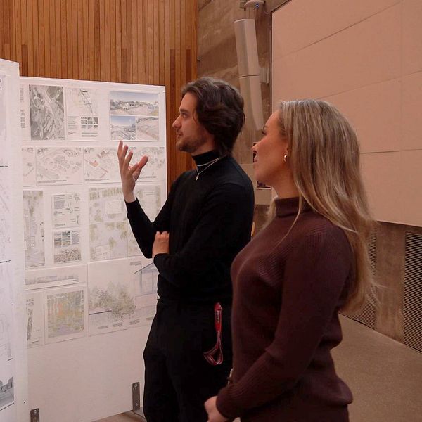 Studenterna Amanda Leander och Alexander Sjölund tittar på en stor affisch med olika ritningar