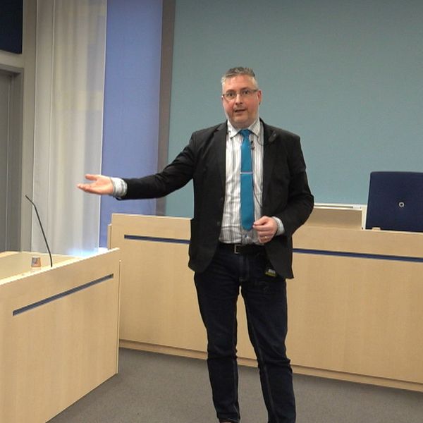 Ola Depui på Jönköpings tingsrätt står i en rättssal och pekar med handen mot sittplatserna.