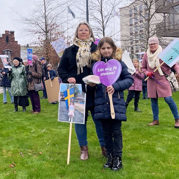 En kvinna och en flicka står mitt i en manifestation