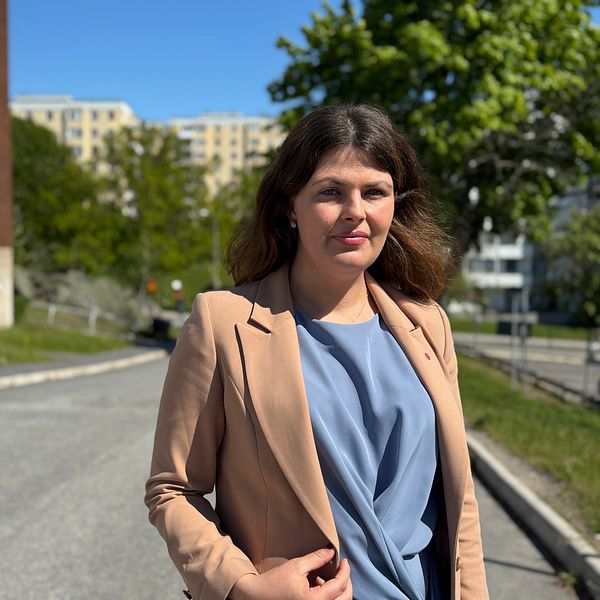 Deniz Butros (V) står utomhus vid bostadshus i Vårberg