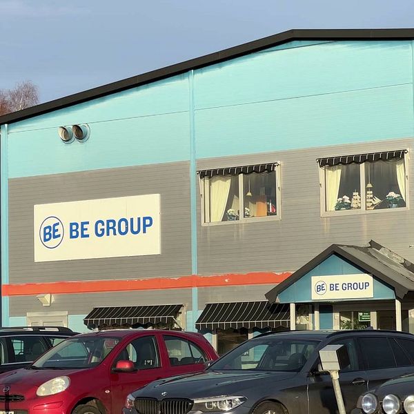 En delad bild med två sektioner: till vänster en porträttbild på kommunalrådet Peter Söderström, till höger en fasad av BE Group:s företag med sin logotyp synlig och parkerade bilar framför.