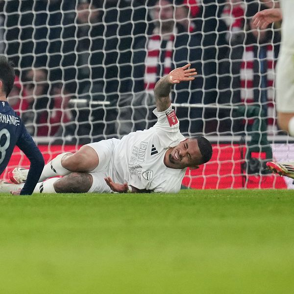 Gabriel Jesus ligger på marken med smärta efter en tackling, medan Manchester Uniteds Bruno Fernandes annan spelare sitter ned bredvid.