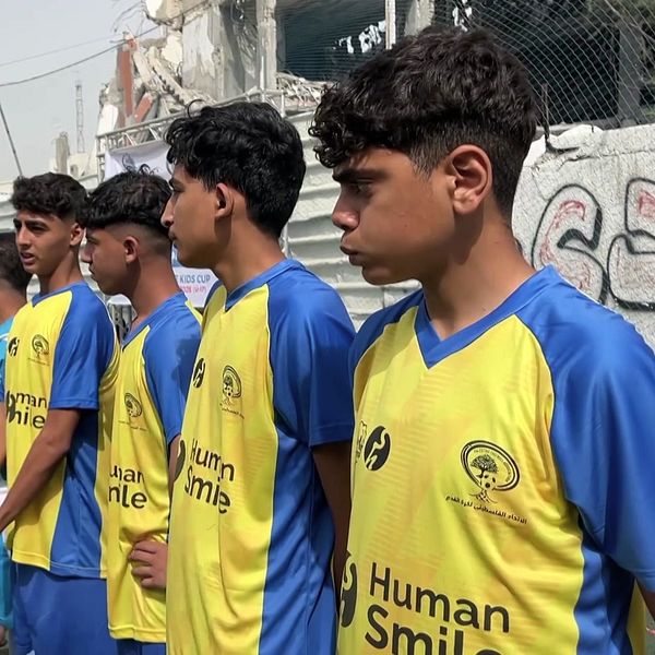 Fotbollsspelare i Gaza står uppställda bland ruiner inför match