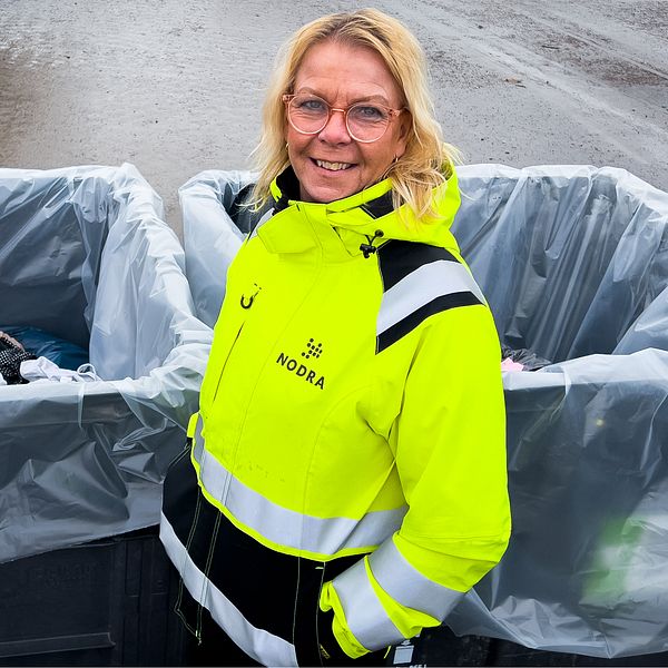 Person i reflexjacka vid två stora sopcontainrar.