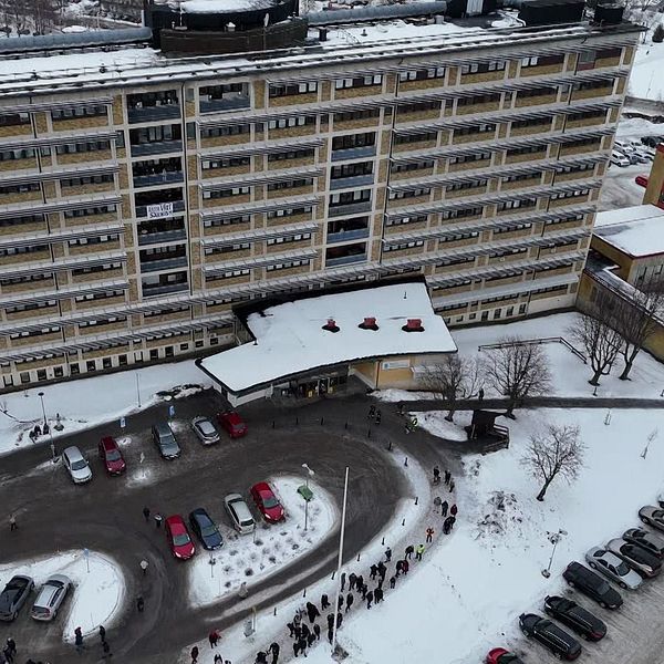 Flygbild av ett stort, snötäckt bostadskomplex med bilar parkerade framför.