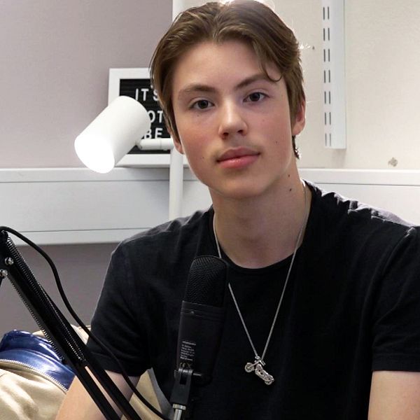 en kille sitter med svart t-shirt vid en mikrofon