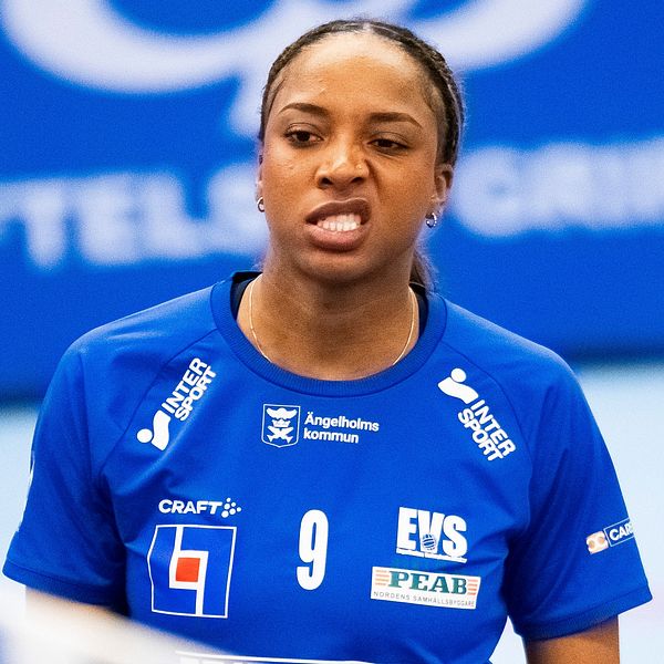 Volleybollspelare i blå tröja nummer 9 vid nätet, inomhussporthall.