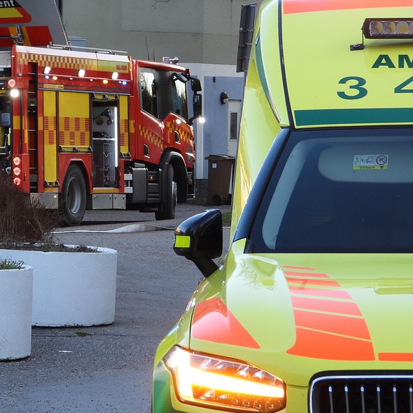 Ambulans och brandbil vid insats, nära byggnader.