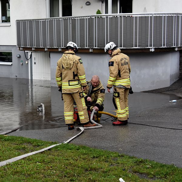 Brandmän pumpar vatten på översvämmad parkering.