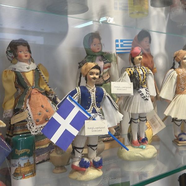 Brabro Rydén står framför sina dockor som står i glasmontrar.