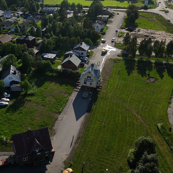 Drönarbild över Malmberget, två hus flyttas med lastbilar på vägen.