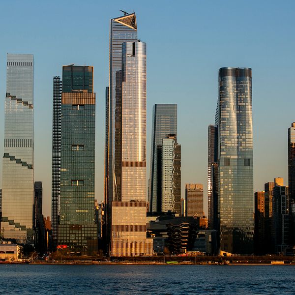 Artisten Brolle spelar på en blågul gitarr samt vy över Manhattans skyline.