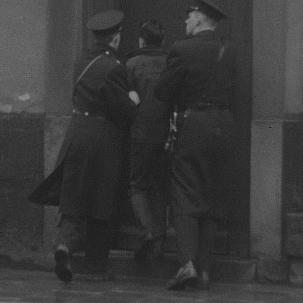 Två poliser håller en ung person i armarna