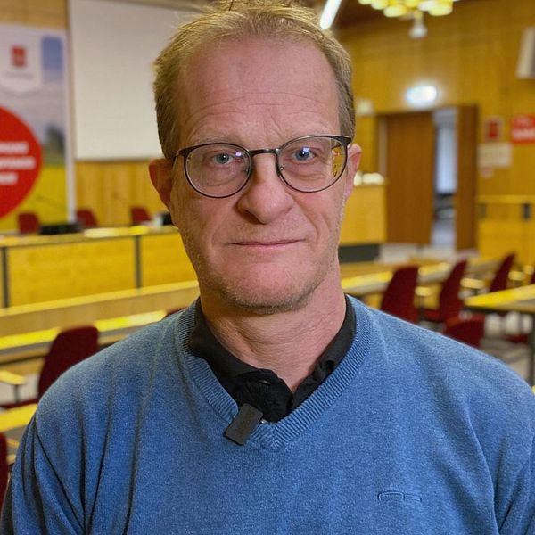 Till vänster syns en hand som häller vatten i ett glas, med bubblor som bildas i glaset. Till höger ser vi en man som står framför en tom konferenssal med stolar i rad.