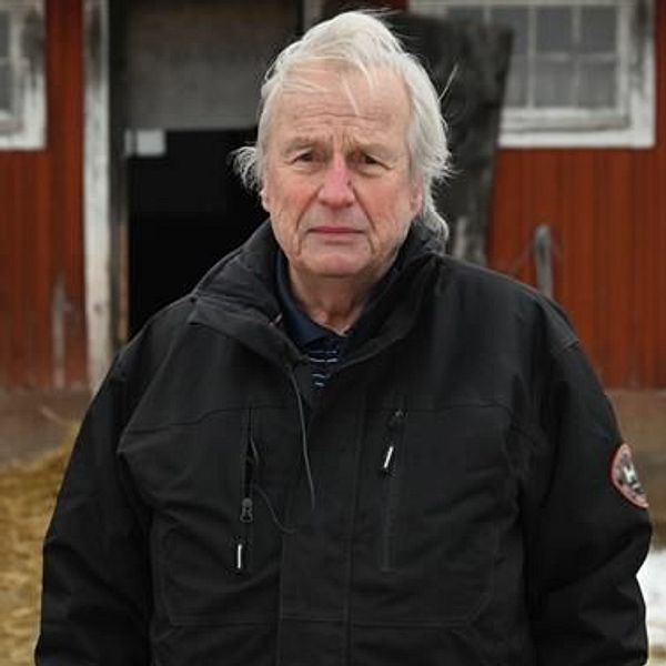 Sven Olsson står utanför en röd ladugård i ett vinterlandskap.