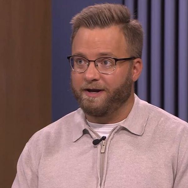 Man i glasögon och ljus tröja talar i tv-studio