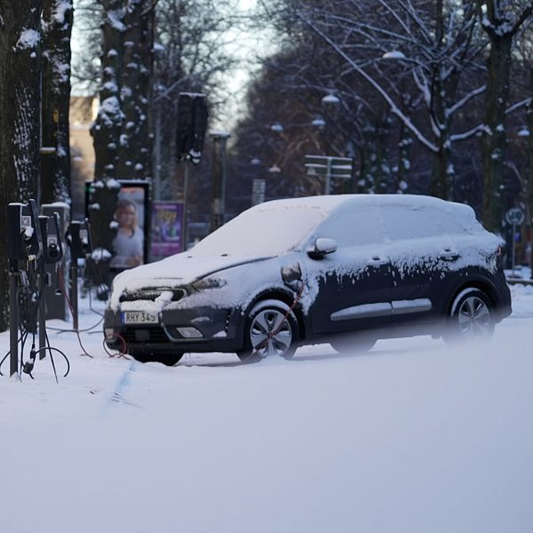 En ensam och igensnöad elbil på en parkering.