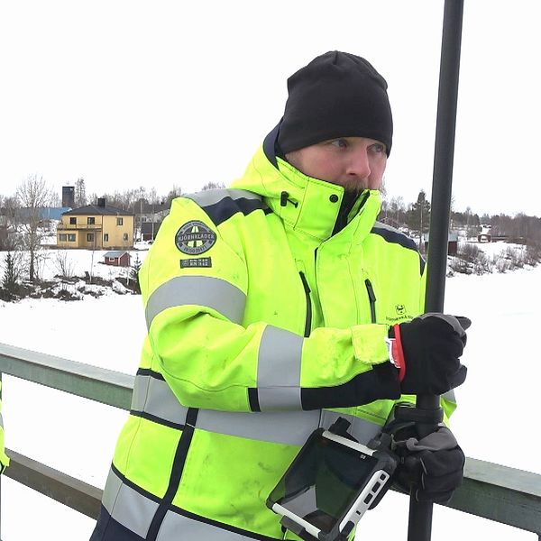 Två män i varselkläder monterar vattenmätare i Övertorneå för att kunna följa vattenflödet inför vårfloden.