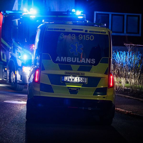 Räddningspersonal och ambulanser på plats vid en utryckning på en mörk väg.