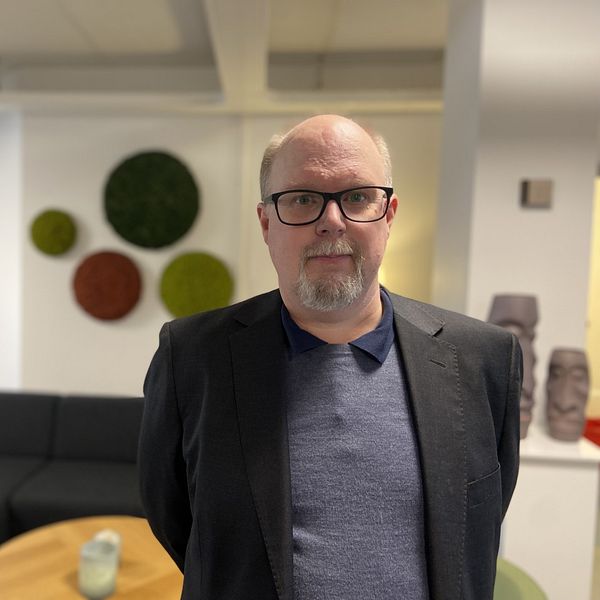 Thomas Gustafsson (S) står i en kontorsmiljö och tittar in i kameran.