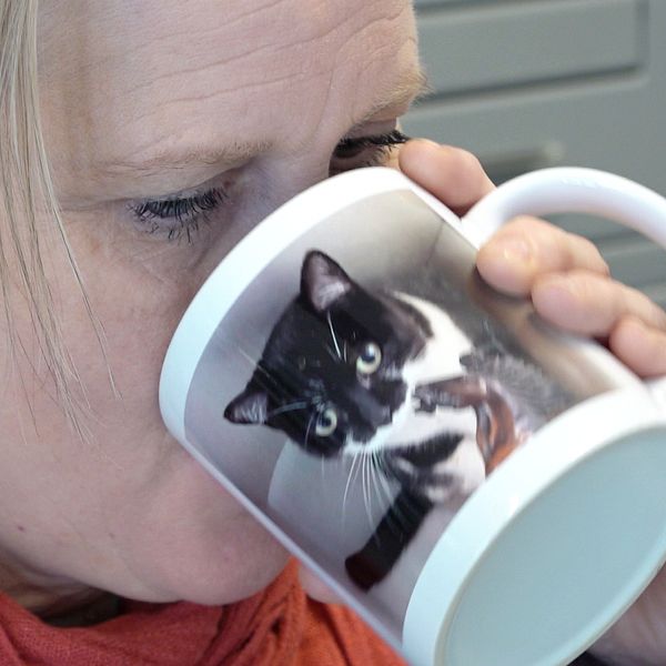 Kvinna dricker från kaffekopp som har en bild på en katt