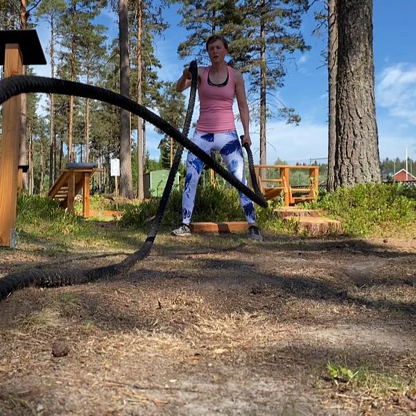 Kvinna som tränar med band i naturen.