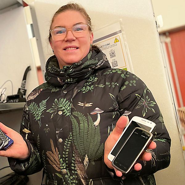 kvinna som håller i gamla mobiltelefoner