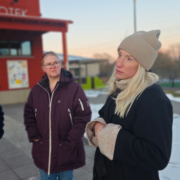 Tre personer står utanför ett bibliotek i vinterkläder.