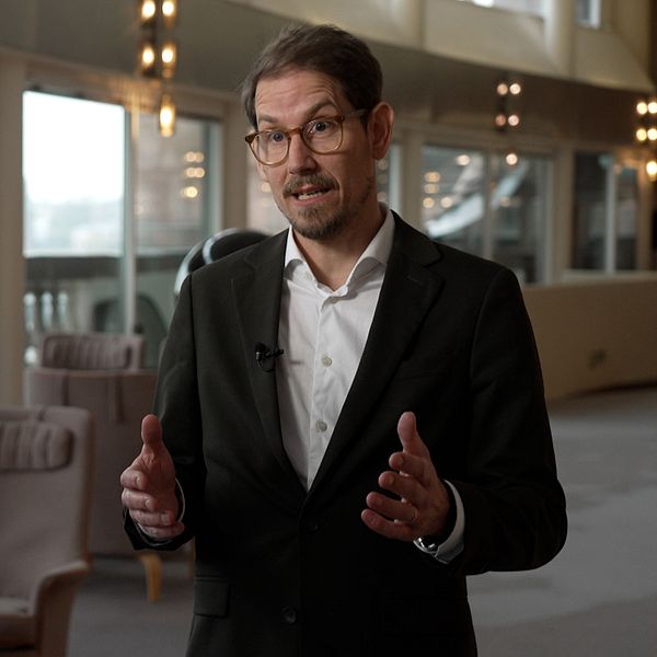 Niels Paarup-Petersen står i ett rum med stora fönster och tomma stolar.