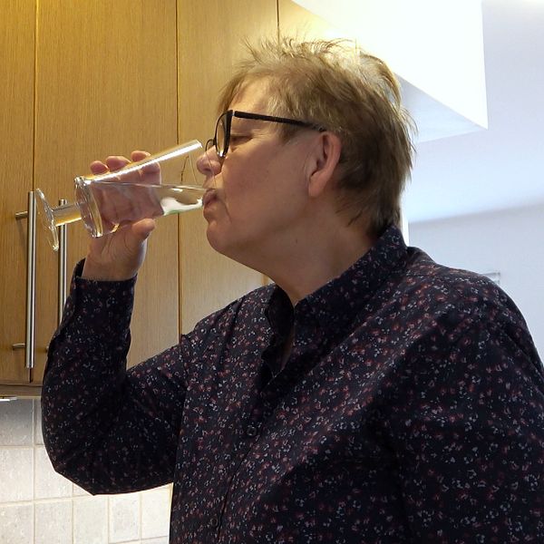 Kvinna dricker ett glas vatten hemma