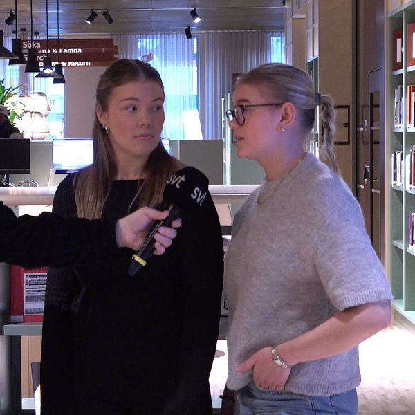 Intervju inne i ett bibliotek, där en man ställer frågor till två kvinnor. I bakgrunden syns bokhyllor.