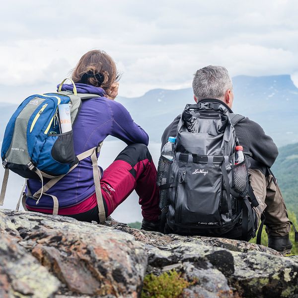 Fjällvandrare i Abisko sitter på en sten och ser på naturen.