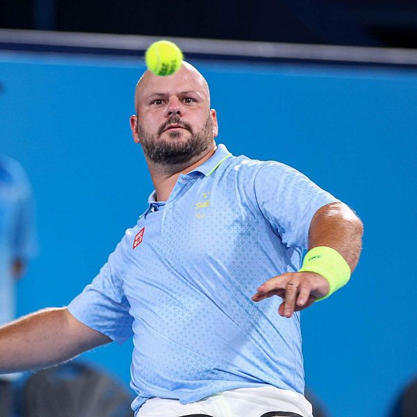 Rullstolstennisspelaren Stefan Olsson med racket i hand och boll framför ansiktet mot blå bakgrund