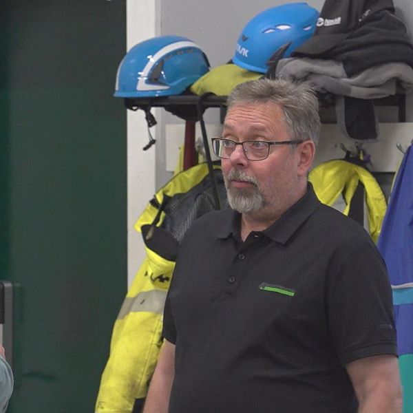 Per Greus och Jesper Mattsson, Markbyggarna Skellefteå. I bakgrunden hänger flera säkerhetskläder, inklusive reflexjackor och hjälmar, vilket tyder på att miljön kan vara en arbetsplats.