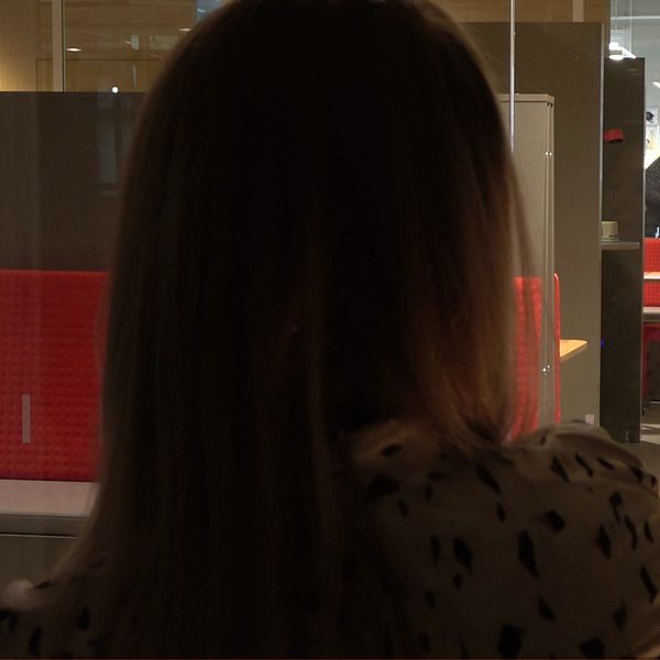 Böcker för modersmålsundervisning på en bokhylla och en anonym lärare bakifrån