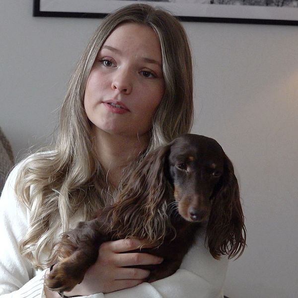 Emilia Nilsson, matte till dvärgtaxen Cooper. håller sin hund i famnen.