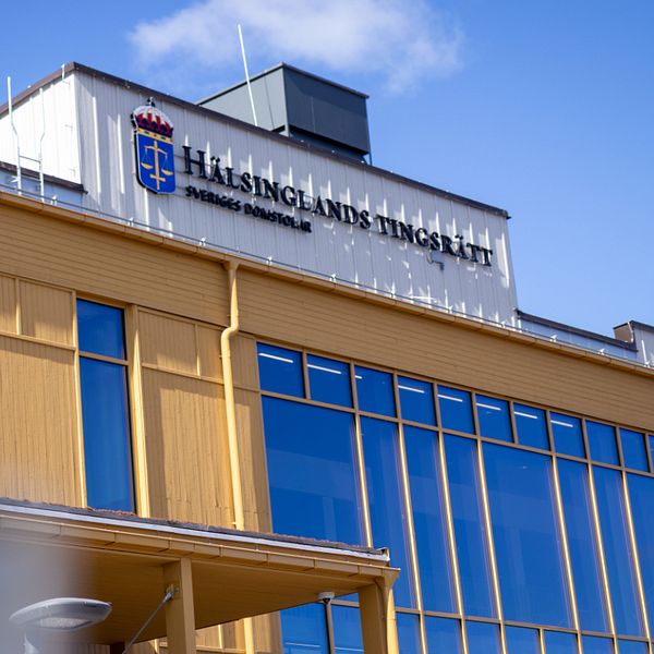 Fasad på Hälsinglands tingsrätt under klarblå himmel.